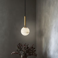 A modern natural marble Aelios chandelier hangs in the foyer above the cabinets.