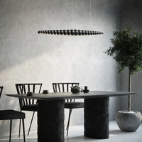 Side view of Nimbus black wood chandelier above black style dining table.